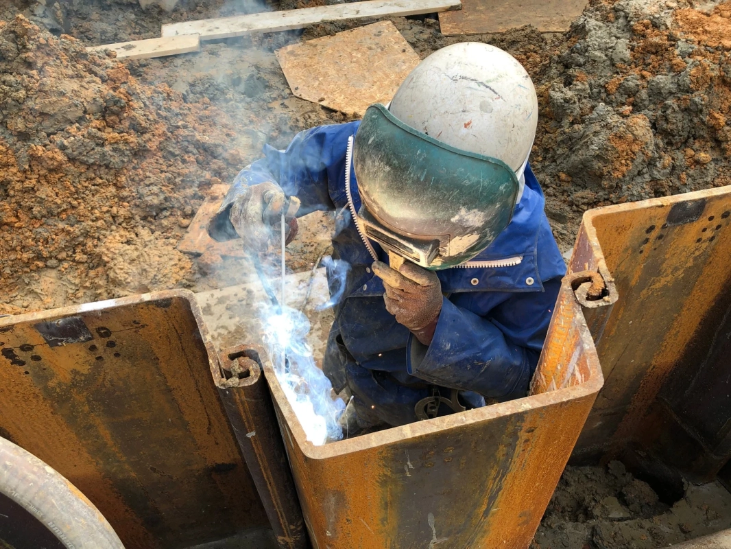 建設現場の溝の中で溶接作業を行う作業員