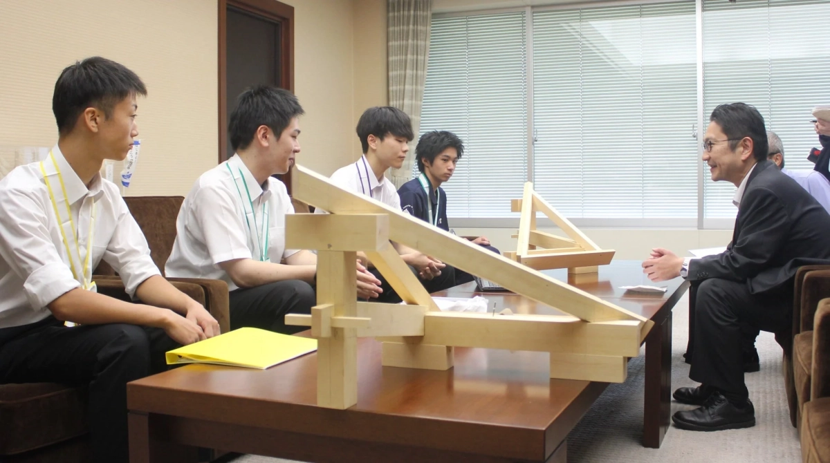 学生が木製の模型を囲んで話し合っている様子