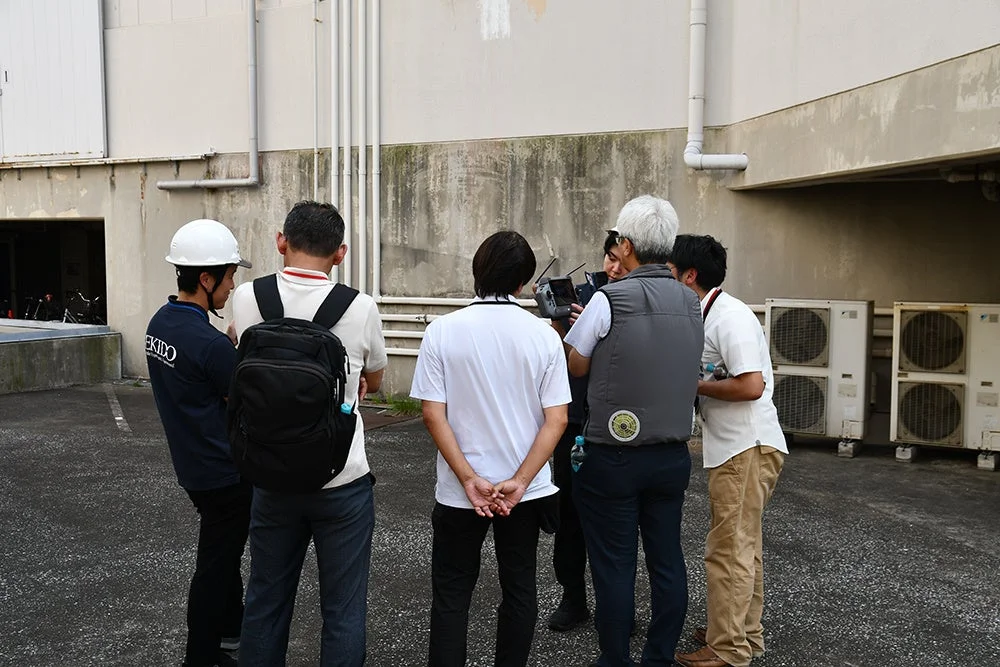 ドローンを囲んで話し合う作業員