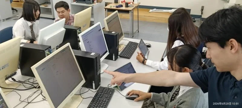 コンピュータ室で学生が共同作業