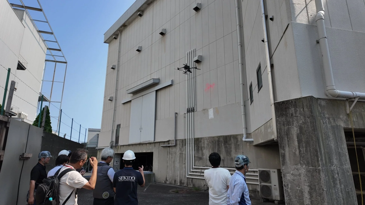 ドローンで建物を点検する作業員